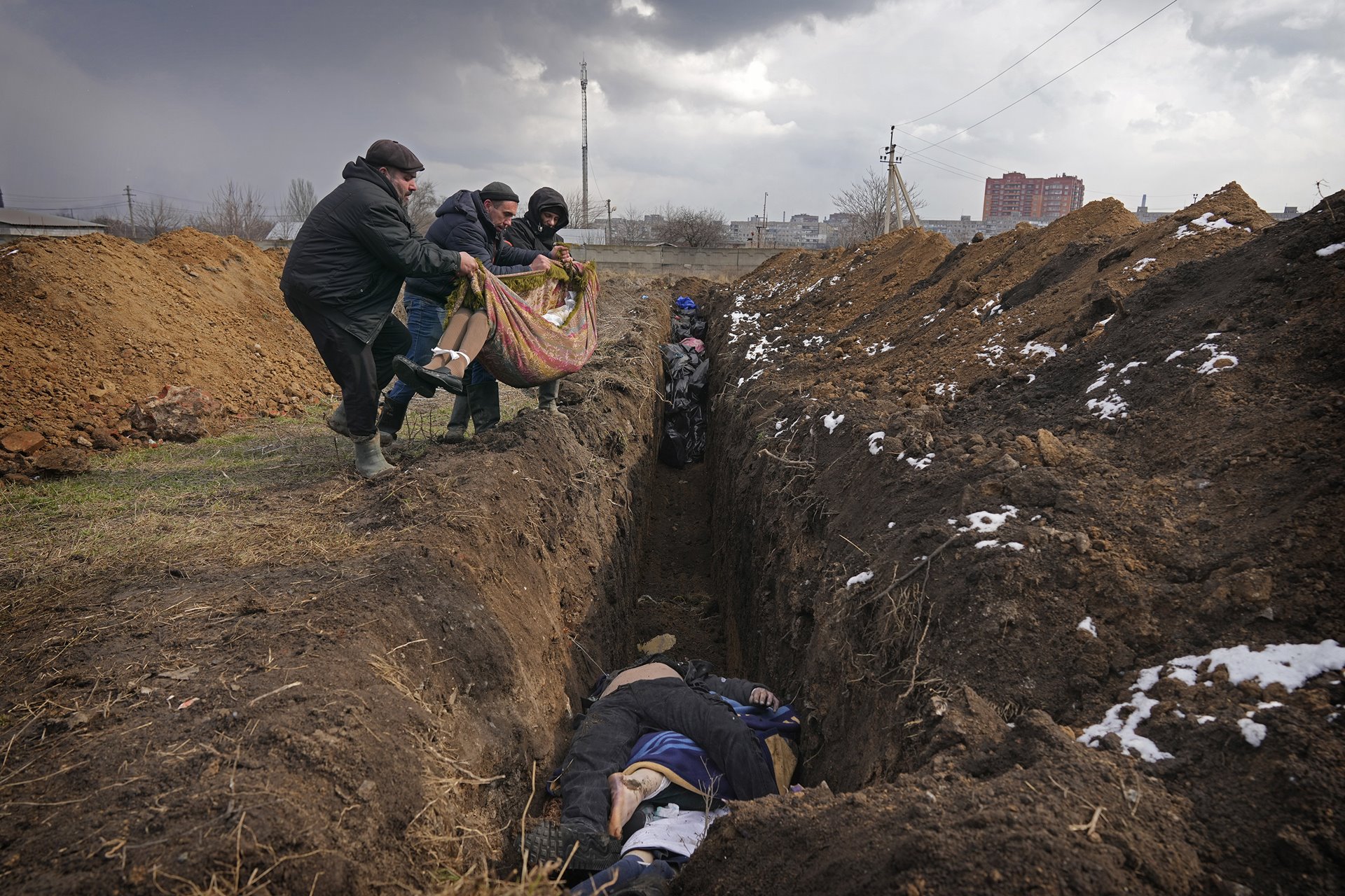 <p>People place dead bodies in a mass grave in an old cemetery in Mariupol. According to the BBC, on some days during periods of heavy Russian shelling, up to 150 people a day were buried in mass graves.</p>

